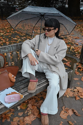 a lady in a white top, a beige wool coat and a pair of white pants